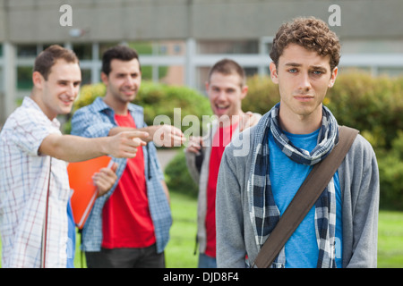 Lonely student being bullied by group of brutish classmates looking hopelessly at the camera Stock Photo