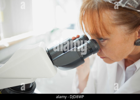 Close up of female scientist looking through a microscope Stock Photo