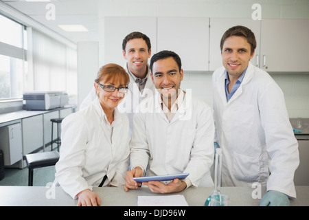 Some scientists standing behind a desk in the laboratory holding a tablet Stock Photo