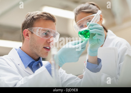 Two students looking at green liquid and taking notes Stock Photo