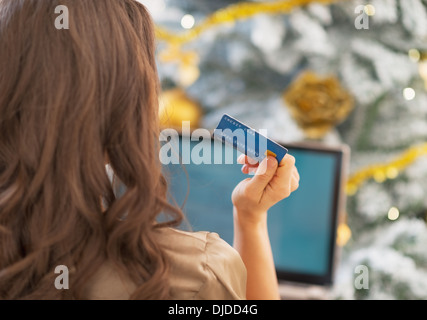 Woman making online shopping in front of christmas tree . rear view Stock Photo