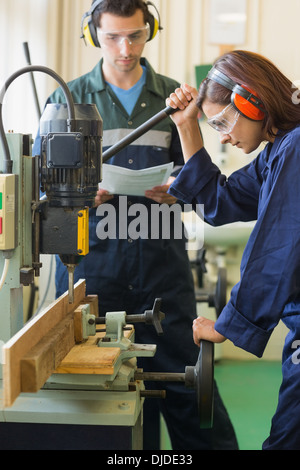 Focused trainee using drill Stock Photo