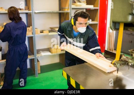 Focused craftsman wearing safety protection using saw Stock Photo