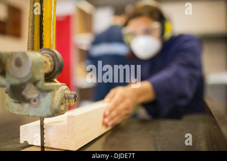 Trainee wearing safety protection using a saw Stock Photo