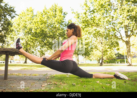 Flexible young woman doing the splits exercise in park Stock Photo