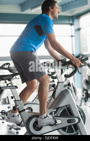 Smiling man working out at spinning class in gym Stock Photo