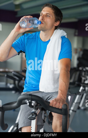 Tired man drinking water while working out at spinning class Stock Photo