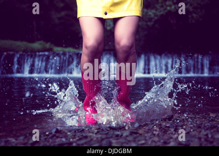 Woman in red gumboots jumping in water Stock Photo