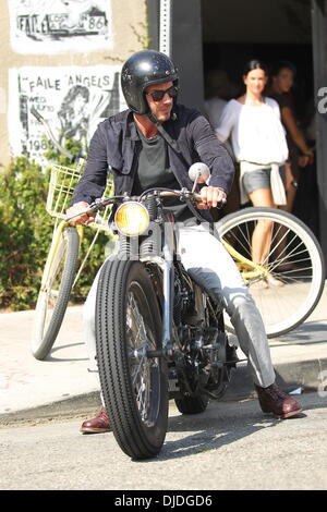 David Beckham returns to his parked Harley Davidson motorcycle after