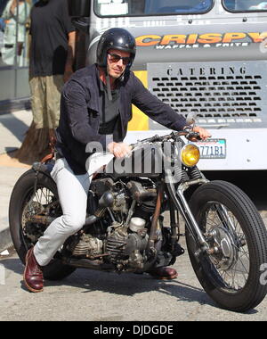 David Beckham returns to his parked Harley Davidson motorcycle after