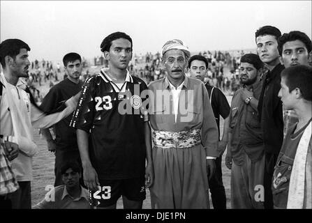 Jun 18, 2003 - Erbil, Iraq - After the Iraqi national football (soccer) team beat the Kurdistan all-city team (3-0) in Erbil, locals rushed to the field to be photographed with the captain of the Iraqi team, NASHAT AKRAM. Nashat Akram Abid Ali made his name as the star player in Iraq's U-17s, managed by Ammo Baba, which finished 2nd in their Asian Cup qualifiers group in July, 2000 Stock Photo