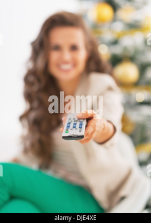 Closeup on tv remote control in hand of young woman in front of christmas tree Stock Photo