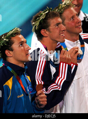 Aug 20, 2004; Athens, GREECE; U. S. Olympic swimmer MICHAEL PHELPS (C)  shows his 100 meter butterfly gold medal Friday Aug. 20, 2004 in Athens,  Greece to the crowd for pictures.  Also pictured is bronze medalist ANDRIY  SERNIOV (L), left, of Ukraine and silver medalist IAN CROCKER of the United  States. Stock Photo