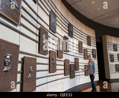 A woman looks at the plaques dedicated to country music stars on a wall inside the Country Music Hall of Fame in Nashville, TN. Stock Photo