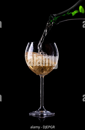 Champagne pouring from bottle into a glass on black background Stock Photo