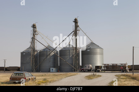 Abandoned car and a Freightliner semi highway truck parked beside grain silos in Moccasin, Montana Stock Photo