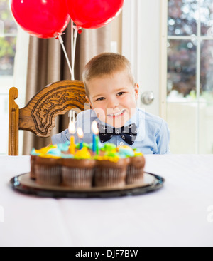 Happy Boy Sitting In Front Of Birthday Cake Stock Photo