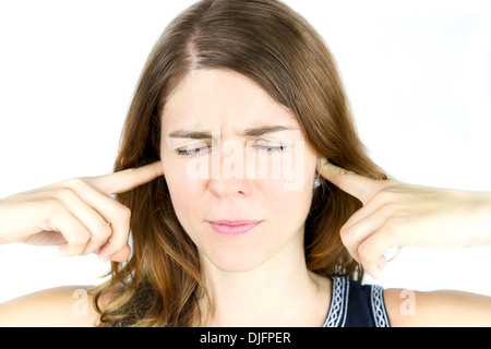 A young woman holds her hands over her ears to block out irritating sounds. Stock Photo