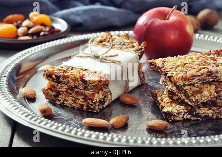 Granola bars on plate with nuts and dried fruits on wooden background Stock Photo