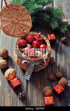 Christmas decorations in wicker basket and fir tree on wooden background Stock Photo