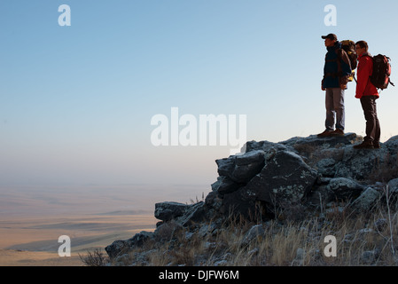 Two hikers enjoying sunrise from top of a mountain Stock Photo