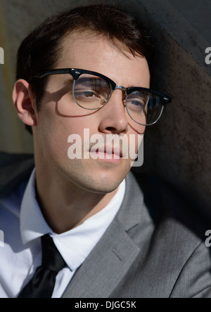 A close-up headshot of a handsome young businessman, wearing vintage eyeglasses. looking away happy and content. Stock Photo