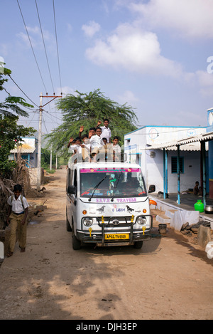 Indian school boys on top of a taxi mini bus being taken to school. Andhra Pradesh, India