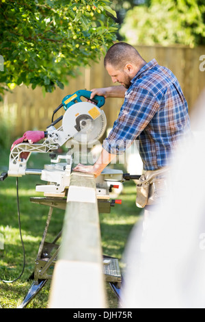 Worker Cutting Wood Using Table Saw At Site Stock Photo