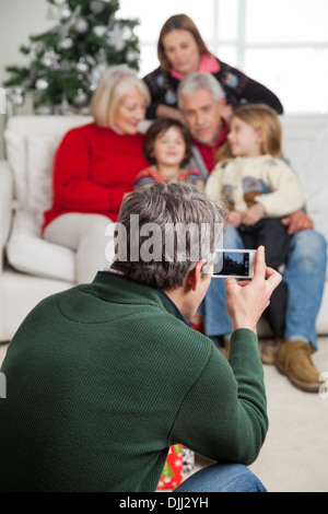 Man Photographing Family Through Smartphone Stock Photo