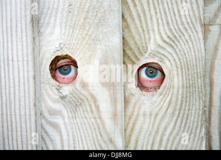 Eye / eyes of a nosey neighbour / neighbor peeping / spying through spy