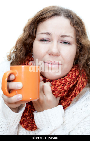 Young illness woman drinking tea with wrapping scarf on neck isolated on white background Stock Photo