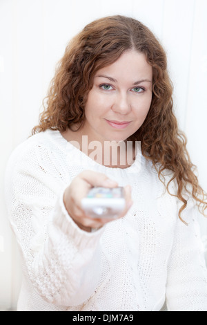 Calm Caucasian woman with tv remote control isolated on white background Stock Photo