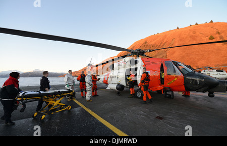 The crew of a Coast Guard MH-60 Jayhawk helicopter prepares to transfer an injured 56-year-old Filipino man to a Kodiak City Fire ambulance crew for further transport to meet a commercial medevac service plane in Kodiak, Alaska, Nov. 27, 2013. The Jayhawk Stock Photo