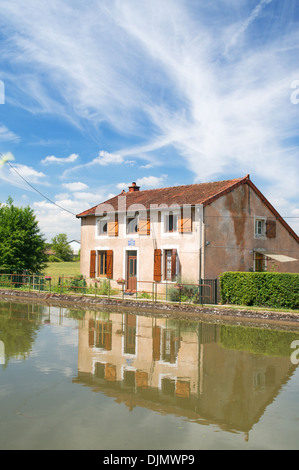 Lock keeper's cottage or house reflected in Canal du Centre Burgundy eastern France Stock Photo
