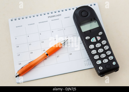 Cordless telephone handset with a blank 2014 calendar and pen pointing to Valentines Day on February 14th Stock Photo