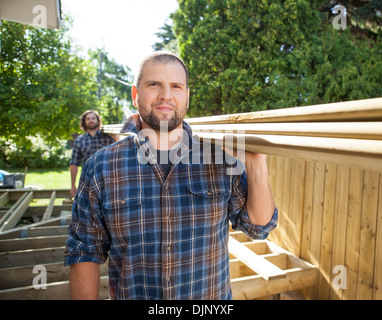 Carpenters Carrying Lumbers On Shoulders At Construction Site Stock Photo