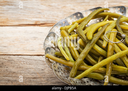 cooked green (French) beans with butter in a metal steamer basket on a rustic wooden table Stock Photo