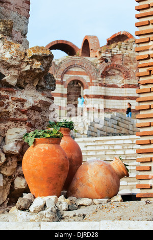 Large pitchers with the plants against the remnants of the ancient church Stock Photo