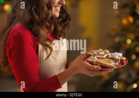 Closeup on young housewife enjoying with plate of christmas cookies Stock Photo