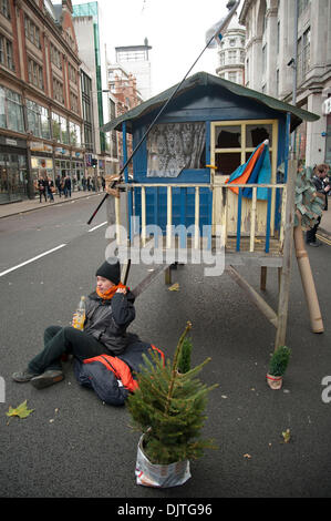 London, UK. 30th November 2013. . Protesters against the proposed Israeli Prawer Plan block the road outside the Israeli Embassy with a small wooden house.Activists have 'locked on' to the structure with bike locks around their necks. The protesters claim that the Israeli government plans to displace 70, 000 Bedouin Palestinians to make room for Israeli settlements. Stock Photo