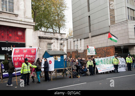 London, UK. 30th November 2013. . Protesters against the proposed Israeli Prawer Plan block the road outside the Israeli Embassy with a small wooden house.Activists have 'locked on' to the structure with bike locks around their necks. The protesters claim that the Israeli government plans to displace 70, 000 Bedouin Palestinians to make room for Israeli settlements. Credit:  Pete Maclaine/Alamy Live News Stock Photo