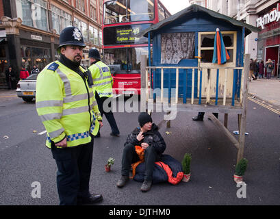 London, UK. 30th November 2013.Protesters against the proposed Israeli Prawer Plan block the road outside the Israeli Embassy with a small wooden house.Activists have 'locked on' to the structure with bike locks around their necks. The protesters claim that the Israeli government plans to displace 70, 000 Bedouin Palestinains to make room for Israeli settlements. Credit:  Pete Maclaine/Alamy Live News Stock Photo