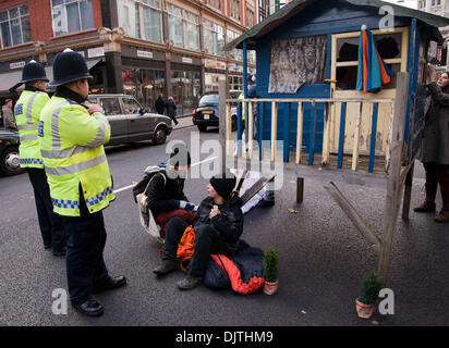 London, UK. 30th November 2013.Protesters against the proposed Israeli Prawer Plan block the road outside the Israeli Embassy with a small wooden house.Activists have 'locked on' to the structure with bike locks around their necks. The protesters claim that the Israeli government plans to displace 70, 000 Bedouin Palestinains to make room for Israeli settlements. Credit:  Pete Maclaine/Alamy Live News Stock Photo