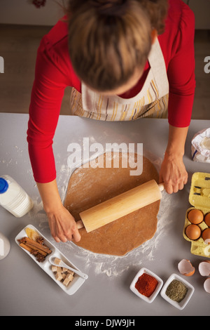 Young housewife rolling pin dough in kitchen Stock Photo