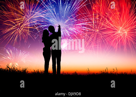 young couple standing on the hill and watching the fireworks Stock Photo