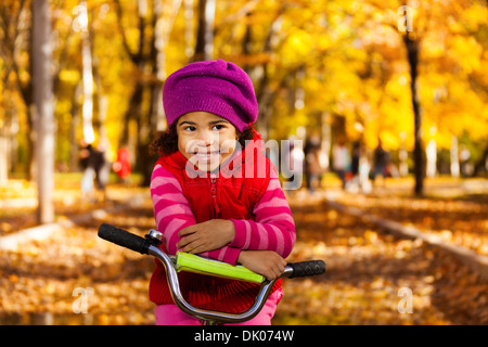 Little black 3 years old black girl riding a bicycle in the park resting on stern Stock Photo