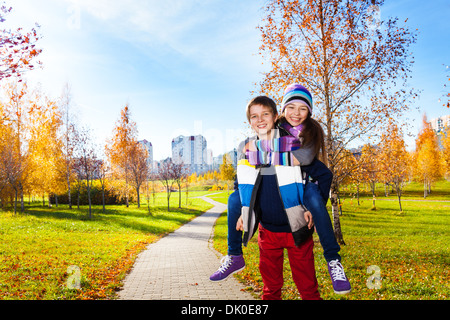 Riding on a boy 10 and 11 years old couple of school kids, in warm autumn clothes Stock Photo