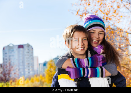 Hugging couple of kids 10 and 11 years old, boy an girl in warm autumn clothes in the park Stock Photo