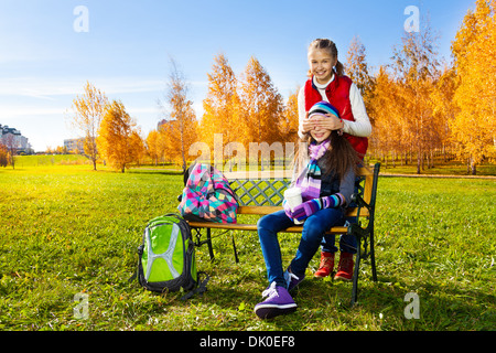 Two happy school age girls playing guessing who am I covering eyes with palms Stock Photo