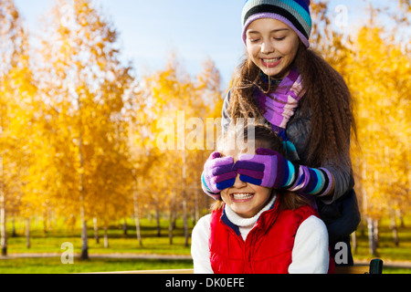 Close portrait of two happy school age happy smiling girls playing guessing who am I covering eyes with palms Stock Photo